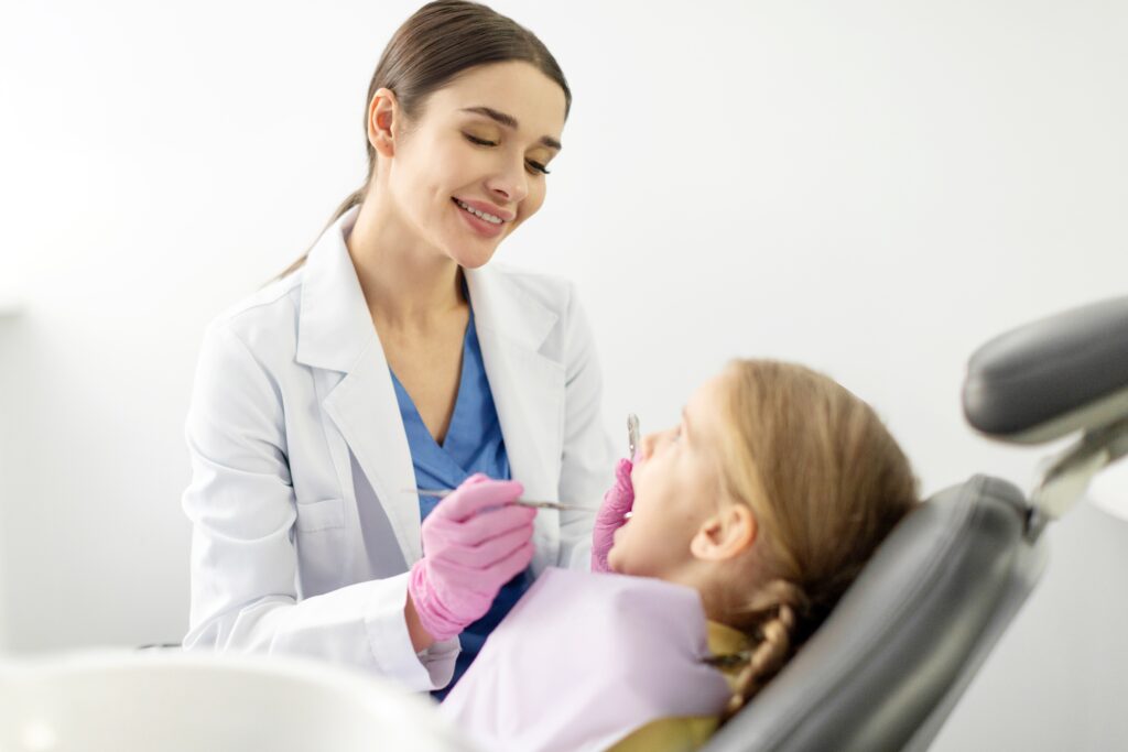 A young female dentist in Tomball treating a young girl in a dental chair, focusing on providing gentle and professional dental care.
